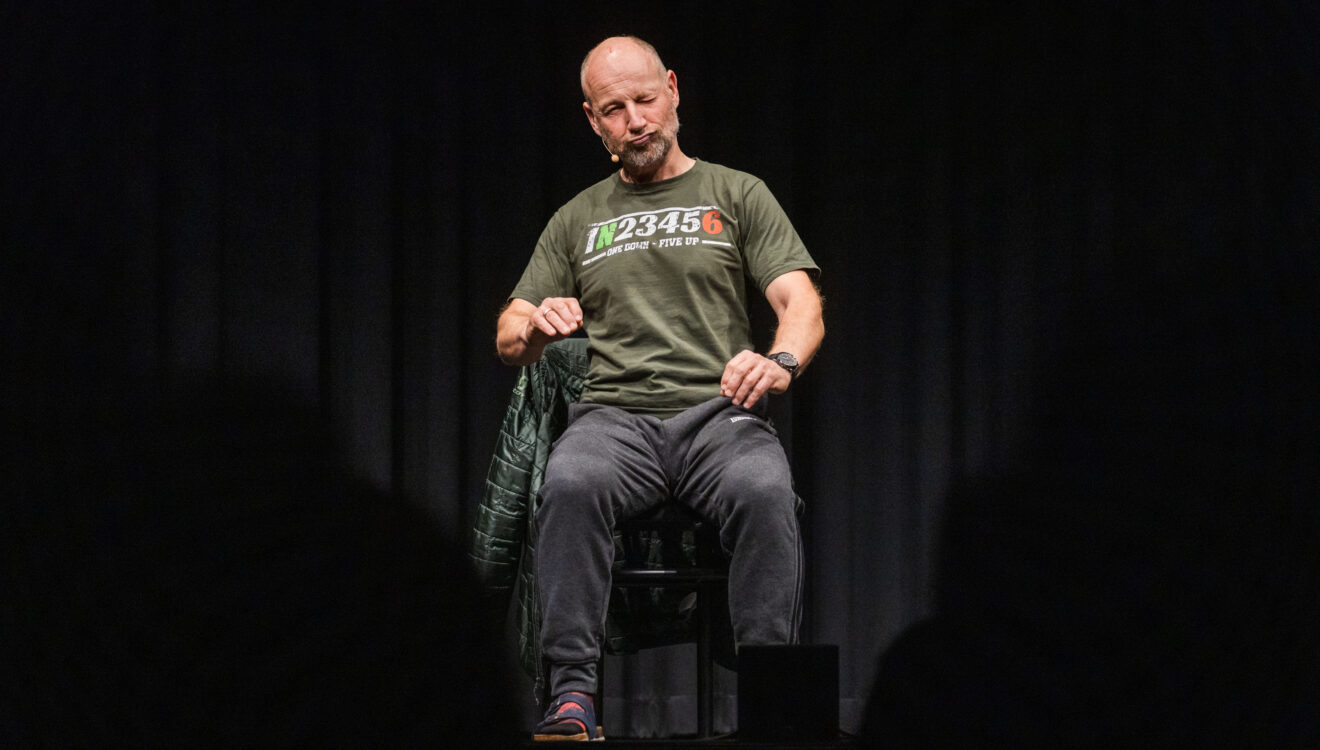 Roland Düringer auf der Bühne sitzend